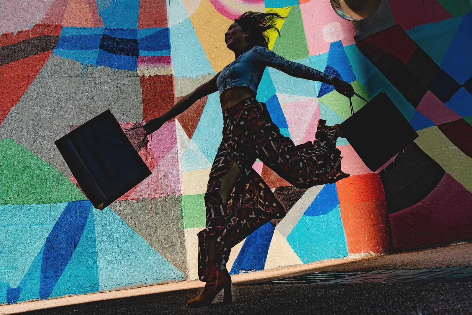 Confident shopper walking with bags against a colorful mural, symbolizing brand trust in everyday choices