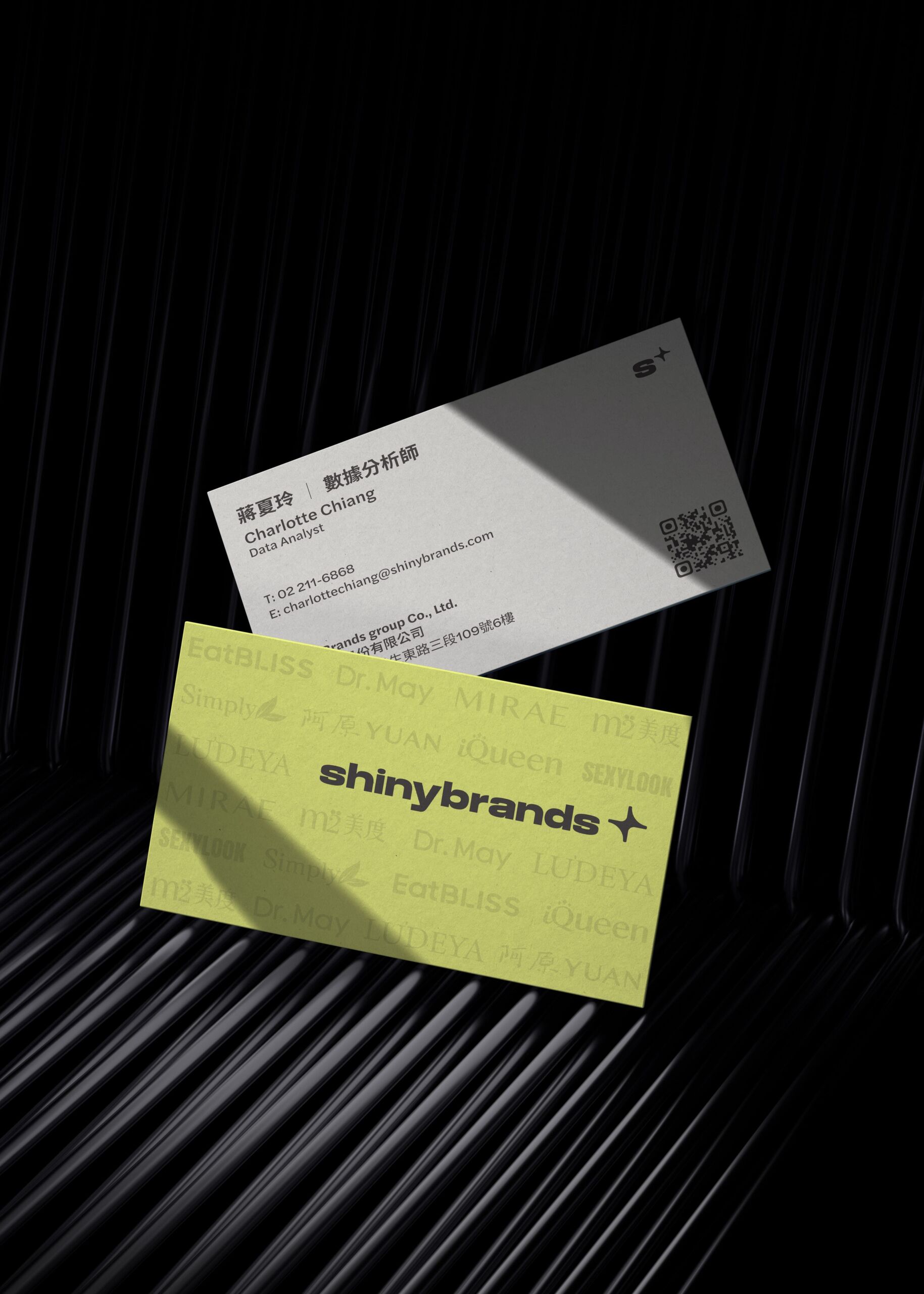 Shinybrands business cards in yellow and gray on a dark surface